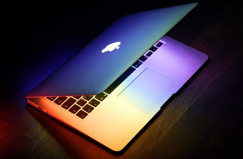 Laptop reviews - A MacBook lit up in rainbow colors on a wooden surface