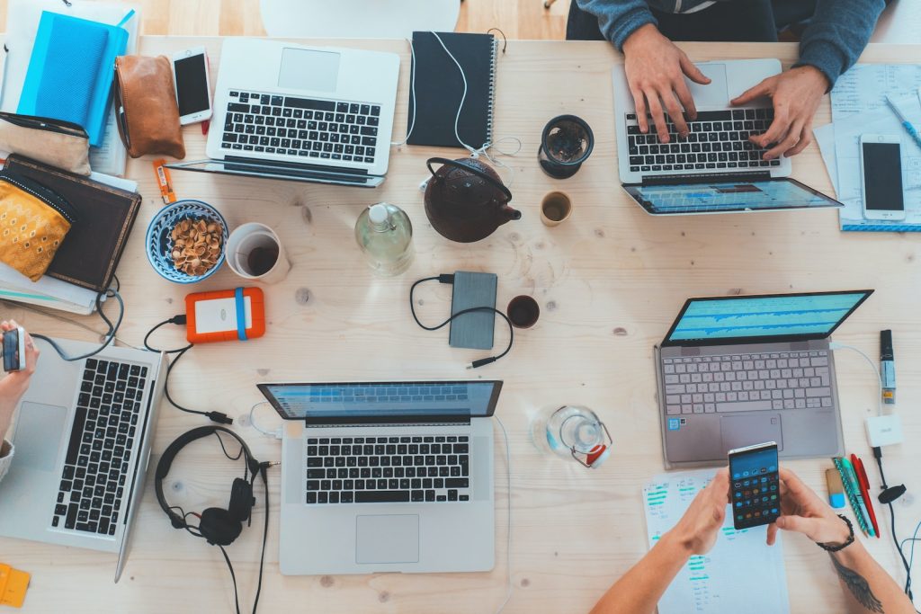 refurbished laptops - people sitting down near table with assorted laptop computers