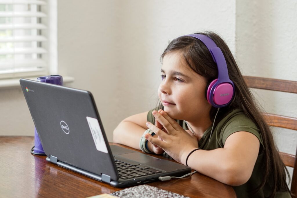 Windows Operating System - a little girl sitting at a table with a laptop